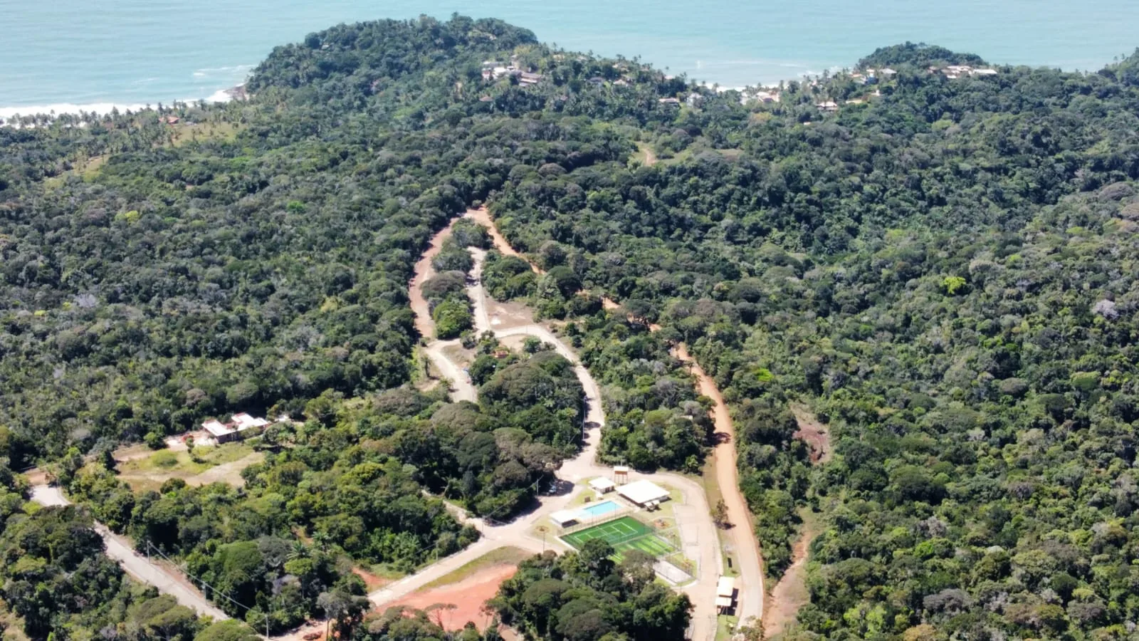 Vista aérea do trajeto até o clube de lazer, em meio à mata, com o mar ao fundo