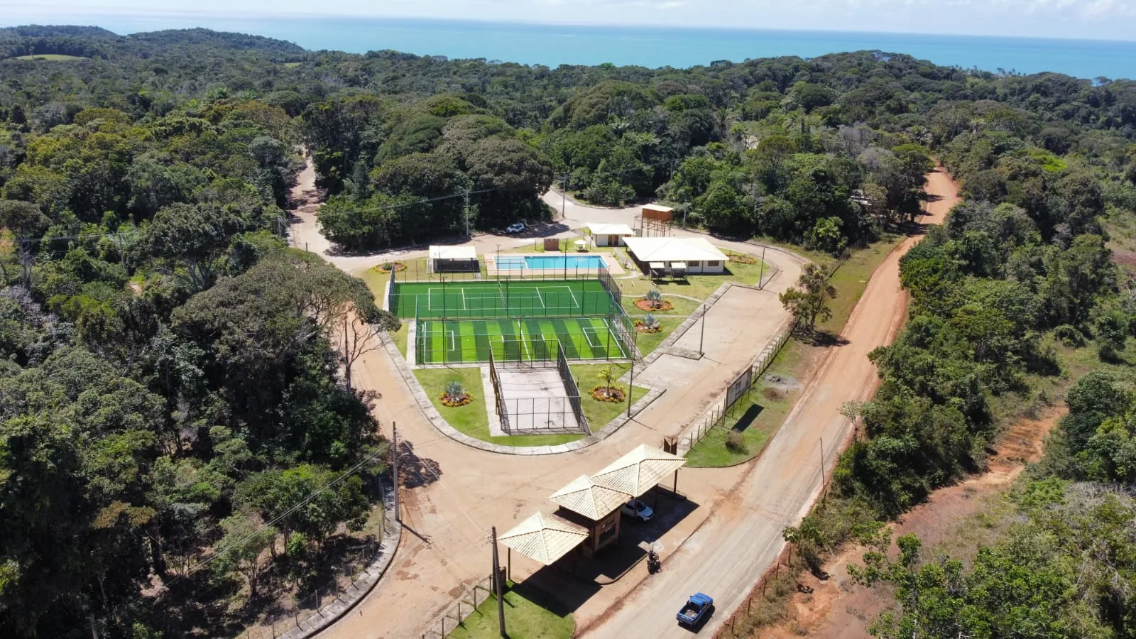 Vista aérea da portaria e do clube de lazer, com o mar ao fundo
